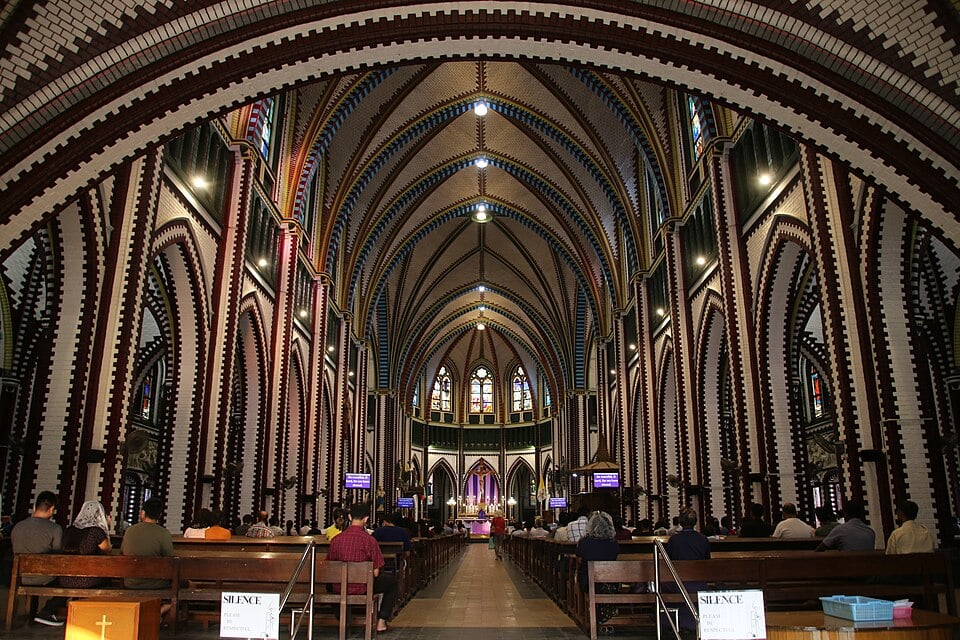 The colourfully vaulted nave of St Mary's Cathedral, Yangon, with worshippers seated in the pews facing the altar.