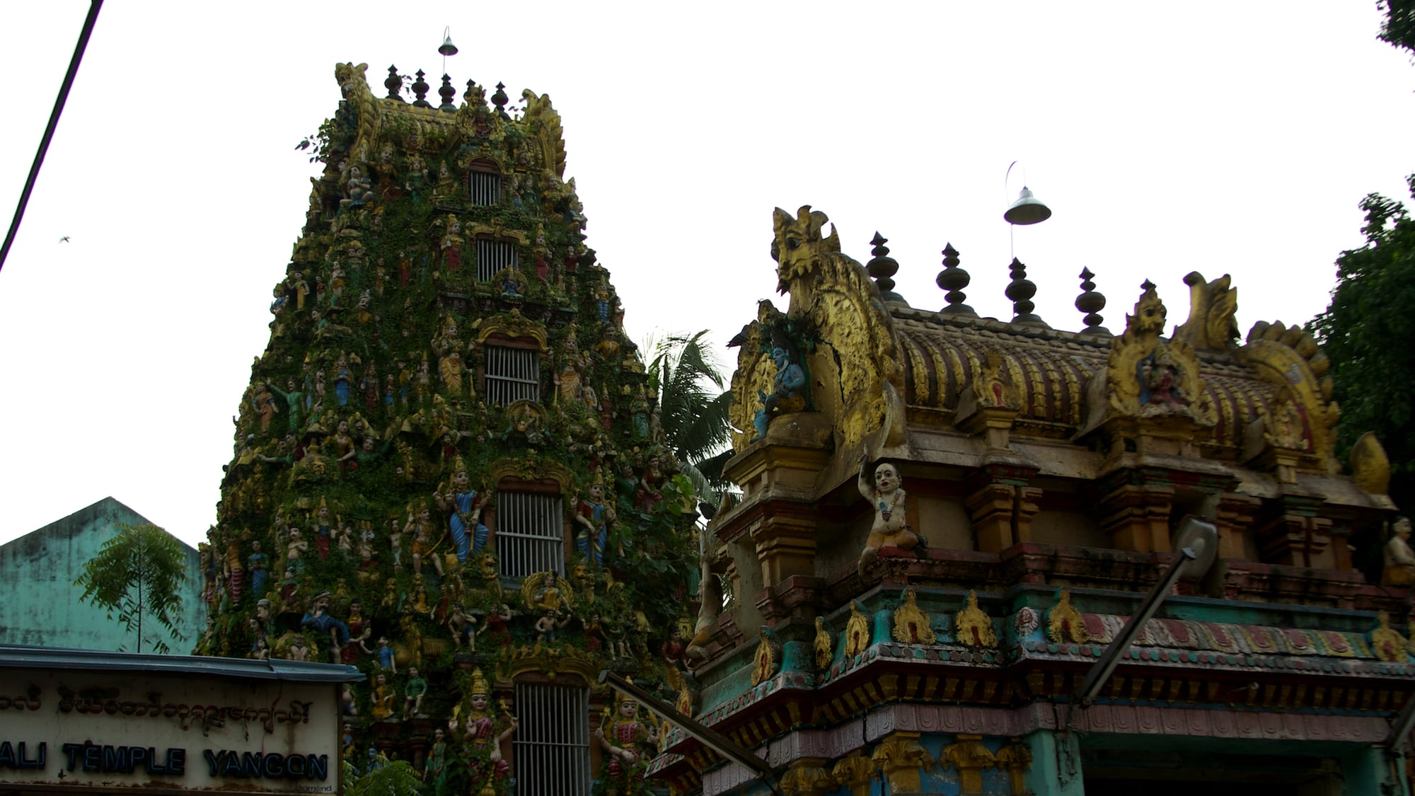 The ornately sculpted, moss-covered gopuram tower of the Sri Kali Temple in downtown Yangon.