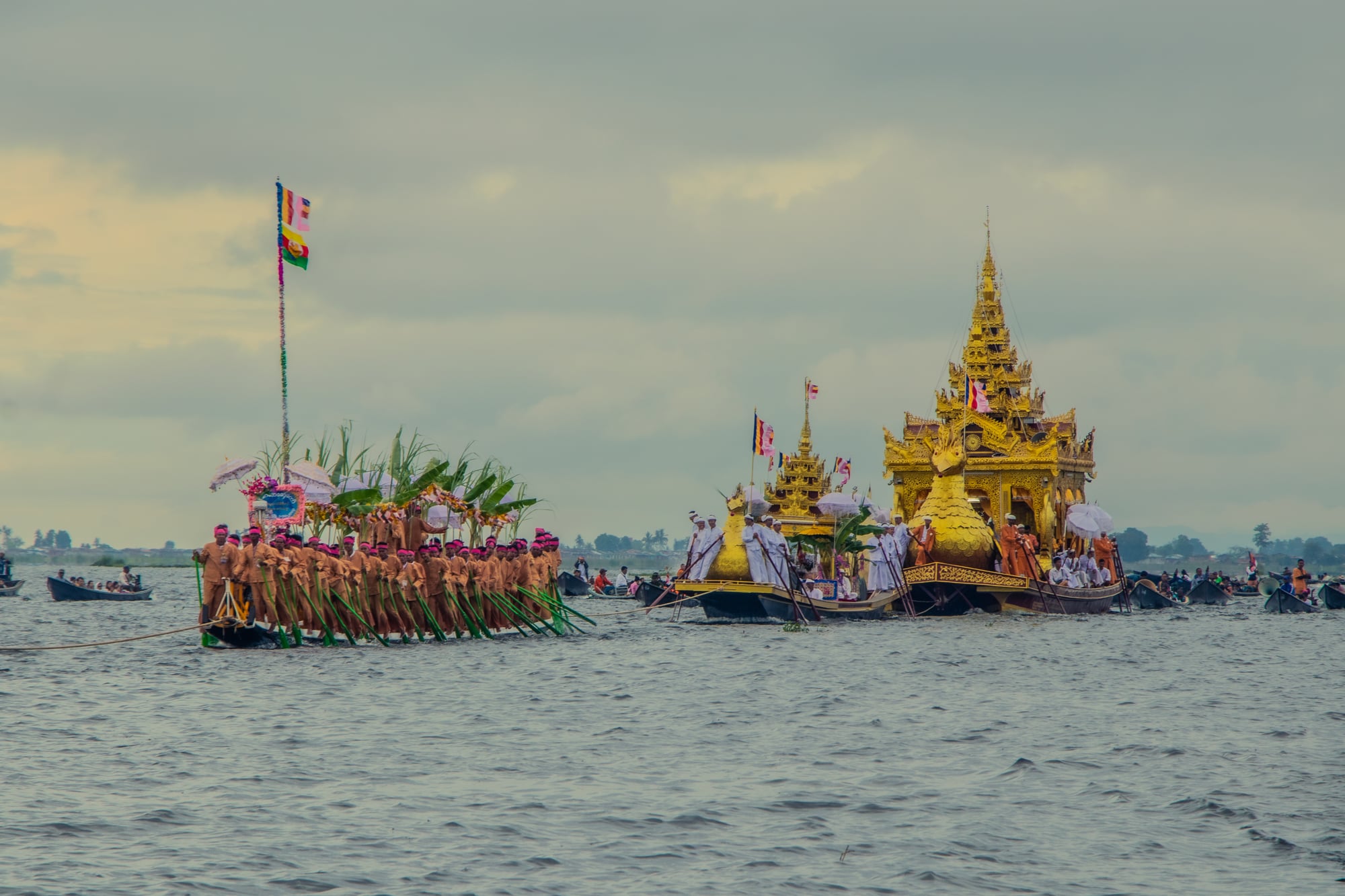 Golden karaweik-shaped barges carrying Buddha images are rowed across Inle Lake during the Phaung Daw Oo Festival, followed by rows of leg-rowers.