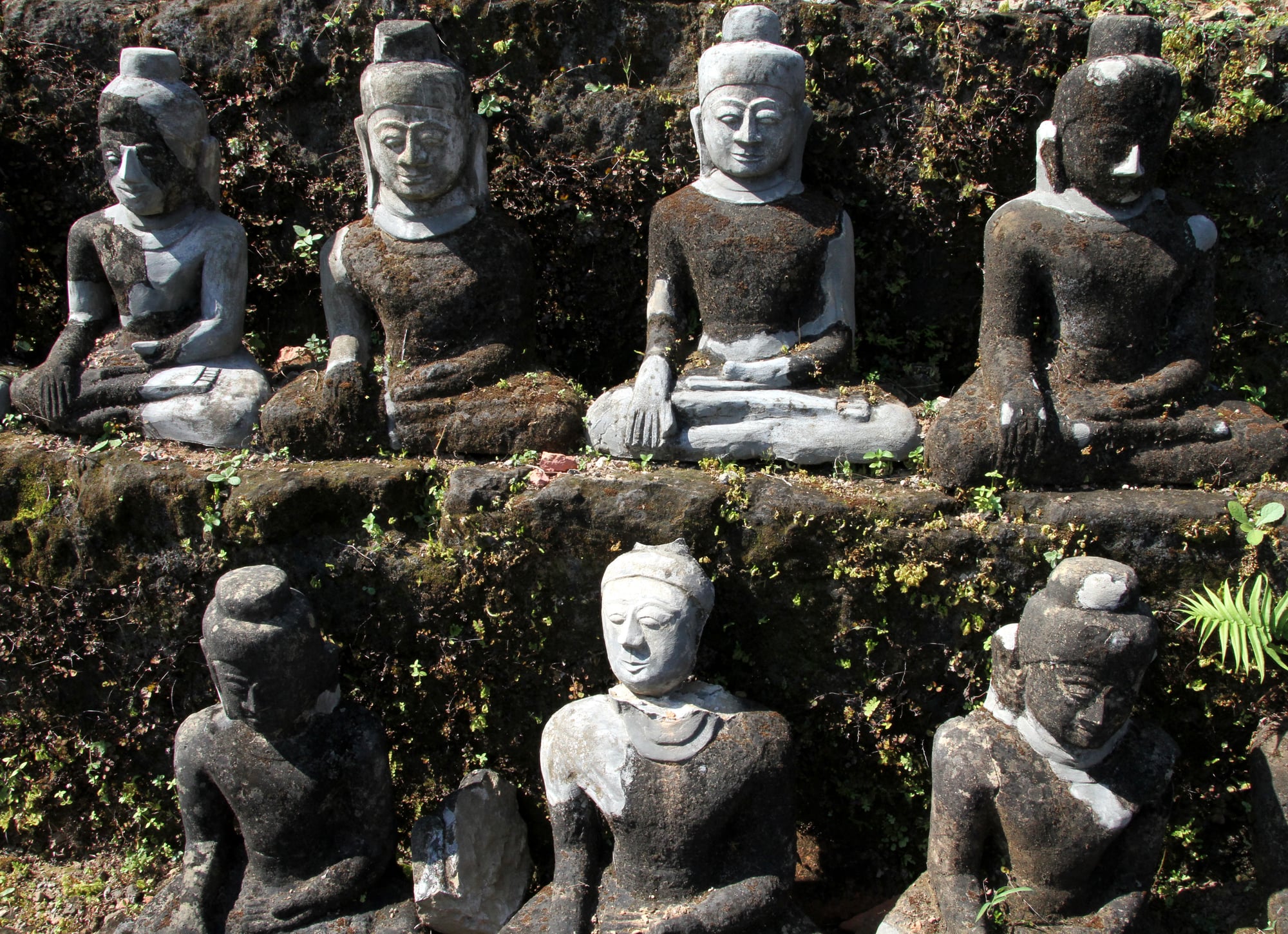 Rows of weathered, moss-covered stone Buddha images sit at Koe-thaung Temple, the largest temple in Mrauk-U.