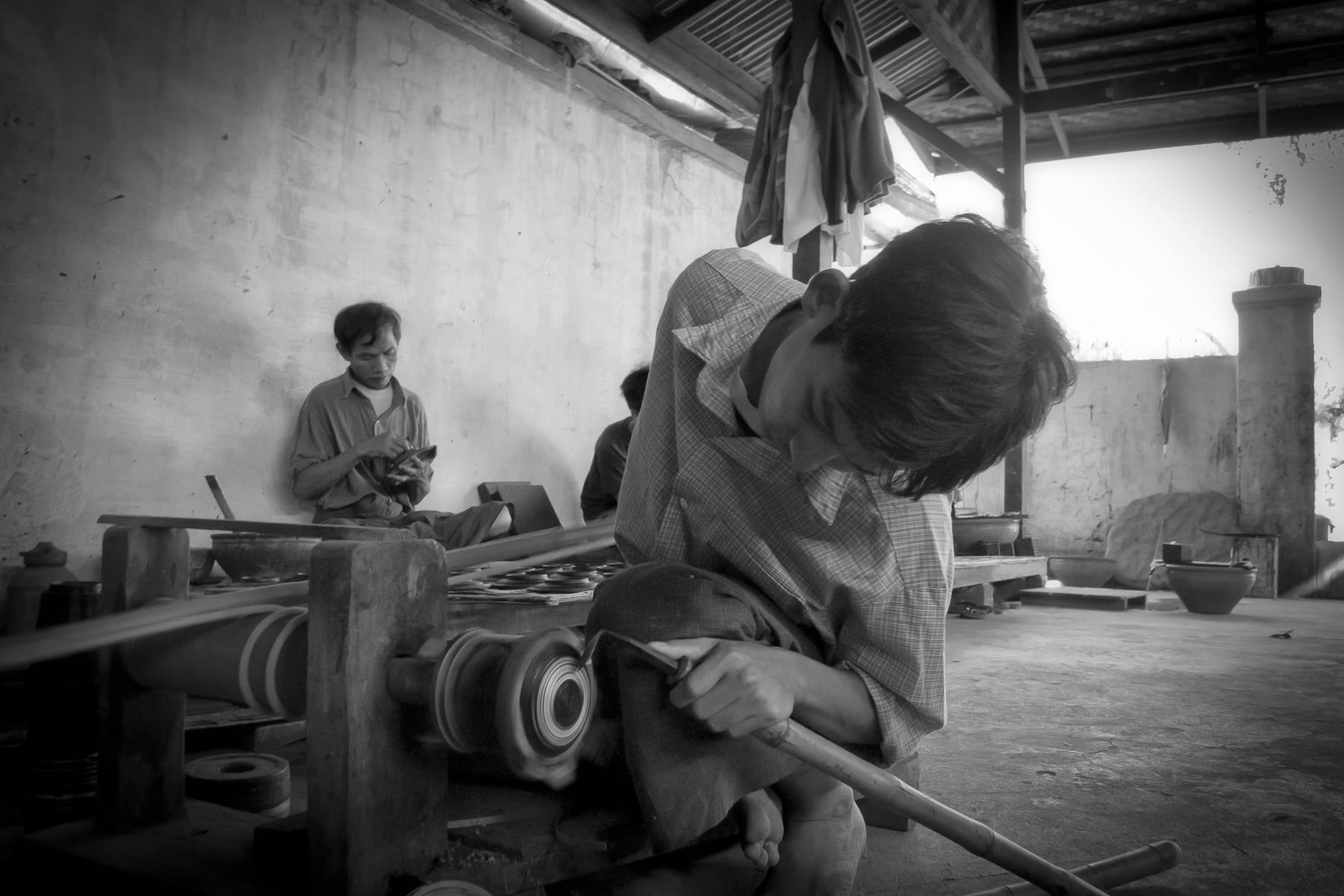 A craftsman bends over a hand-turned lathe, engraving a lacquerware piece by hand in a Bagan workshop.