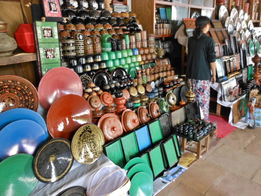 Shelves of colourful lacquerware bowls, trays and boxes in red, black, green and gold on display in a Bagan shop.