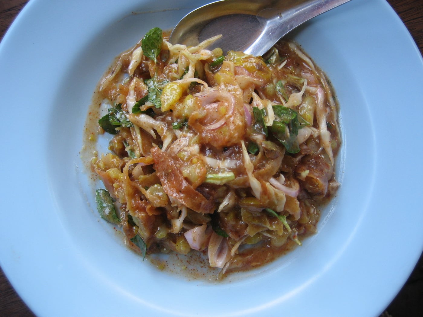 A plate of samosa thoke, crushed samosa pieces mixed with cabbage and onion in a tangy dressing.