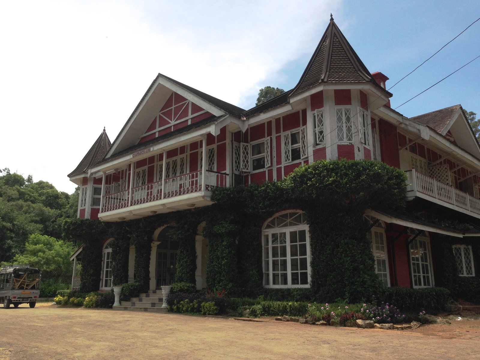 The Candacraig, a red-and-white timber colonial mansion with a turret, its lower floor covered in climbing vines, in Pyin Oo Lwin.