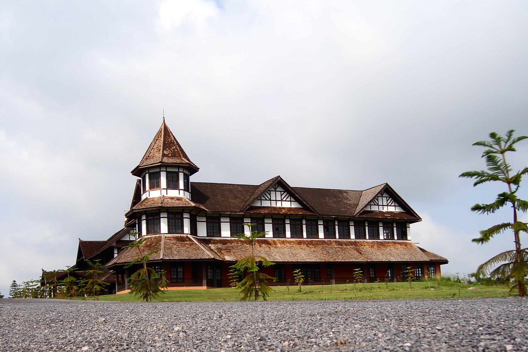 The Governor's House, a Tudor-style colonial mansion with a turret and dark timber gables, stands on a grassy hilltop in Pyin Oo Lwin.