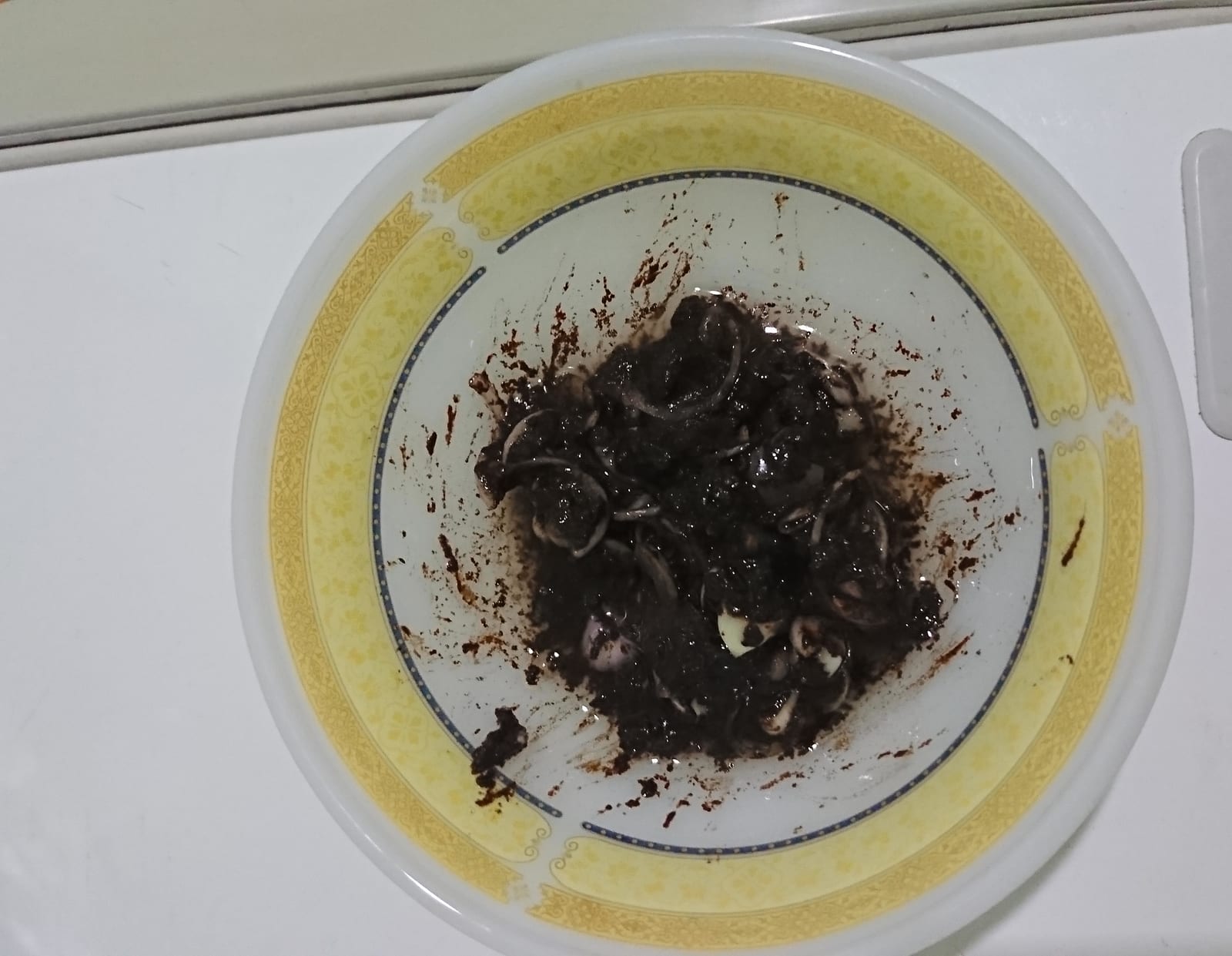 A bowl of pon ye gyi, a dark fermented bean paste mixed with sliced onion.