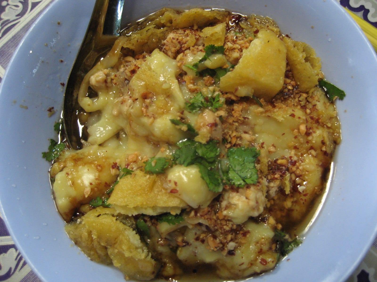 A bowl of warm Shan tofu and fried tofu salad, dressed with chilli oil and topped with peanuts and coriander.