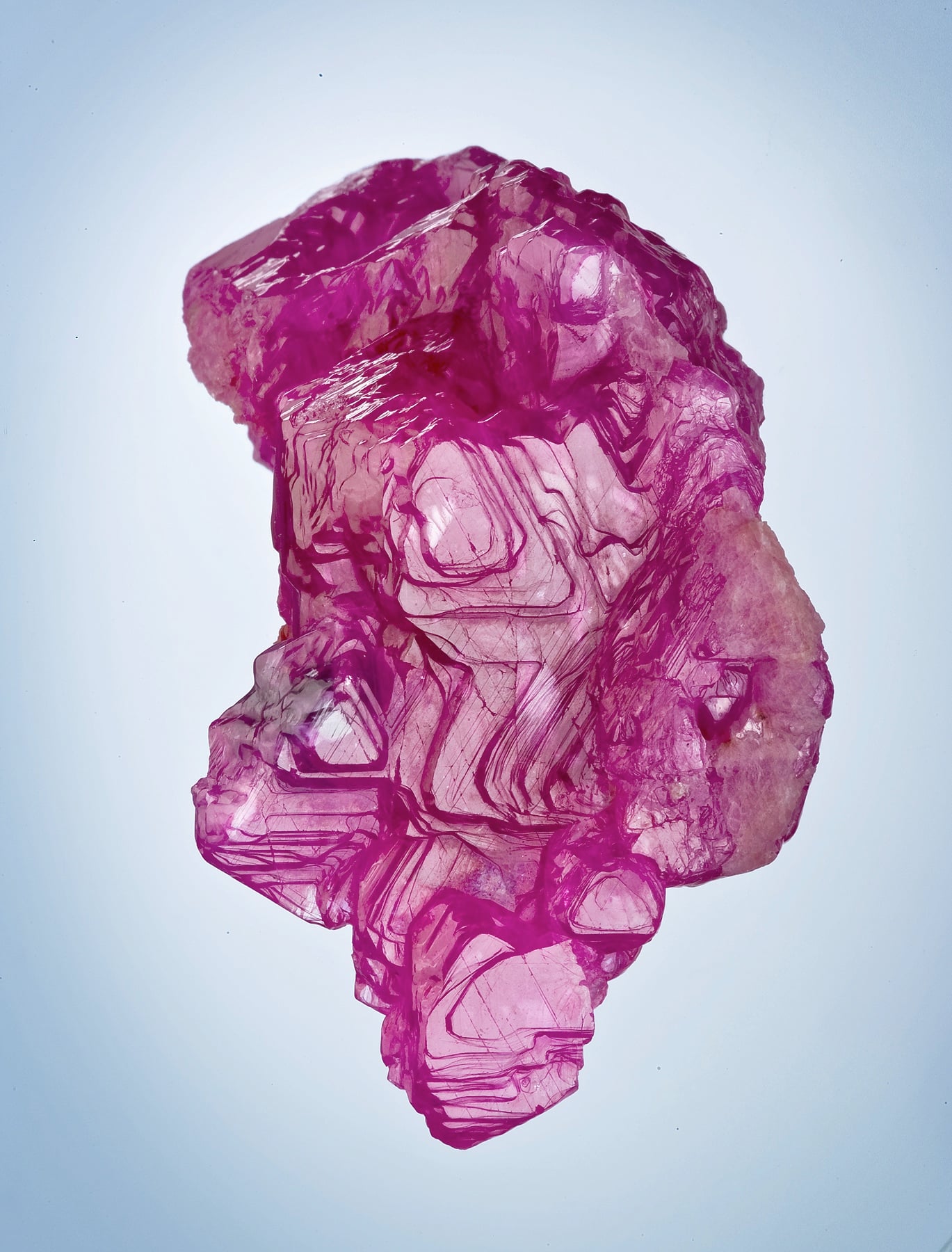 A rough ruby crystal from Mogok, its facets glowing in varying depths of pink and red.