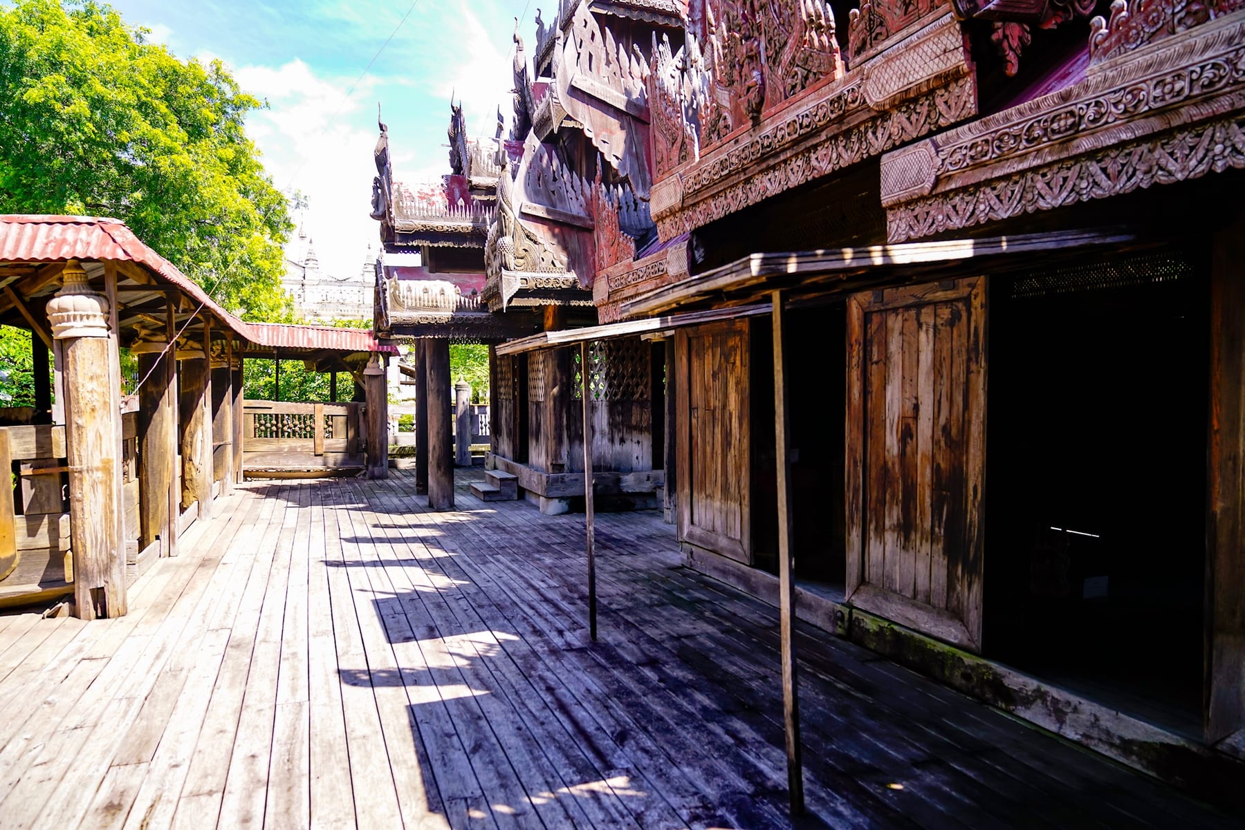 The ornately carved silver and red facade of Yokesone Monastery in Salay, with a wooden deck in the foreground.