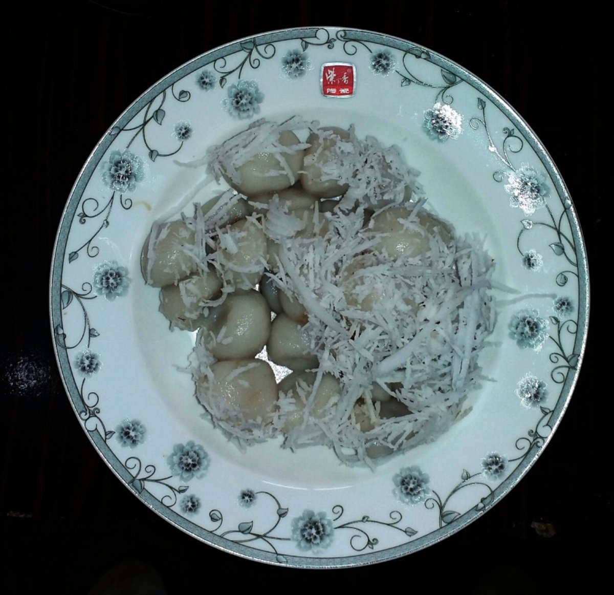 A plate of mont lone yay baw, boiled glutinous rice balls topped with shredded coconut.