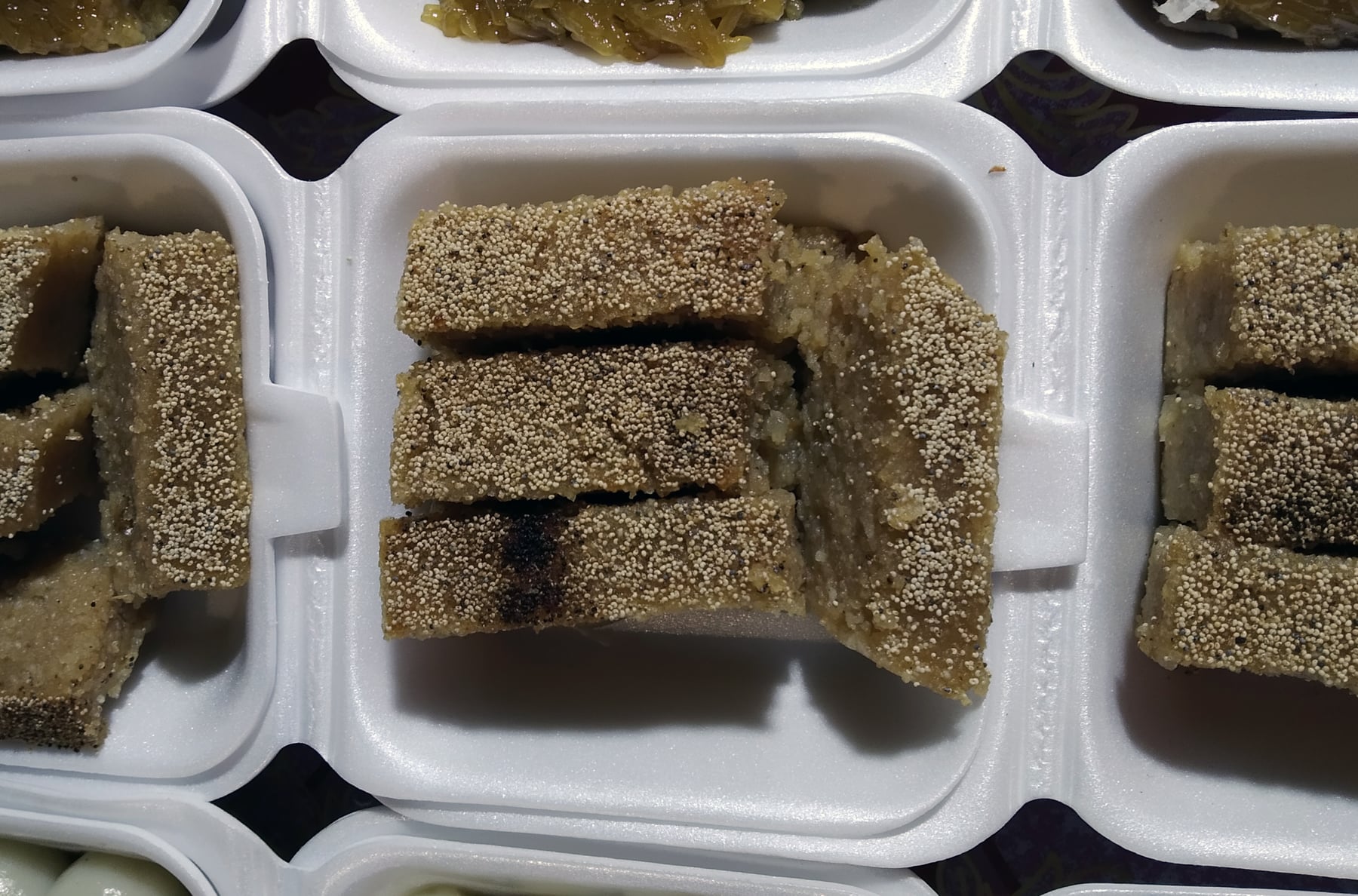 Sliced bars of sanwin makin, a dense semolina cake topped with sesame seeds.