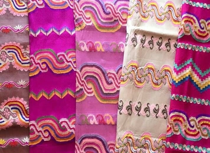 Five panels of acheik fabric in pink, magenta and cream, each woven with intricate wave patterns.