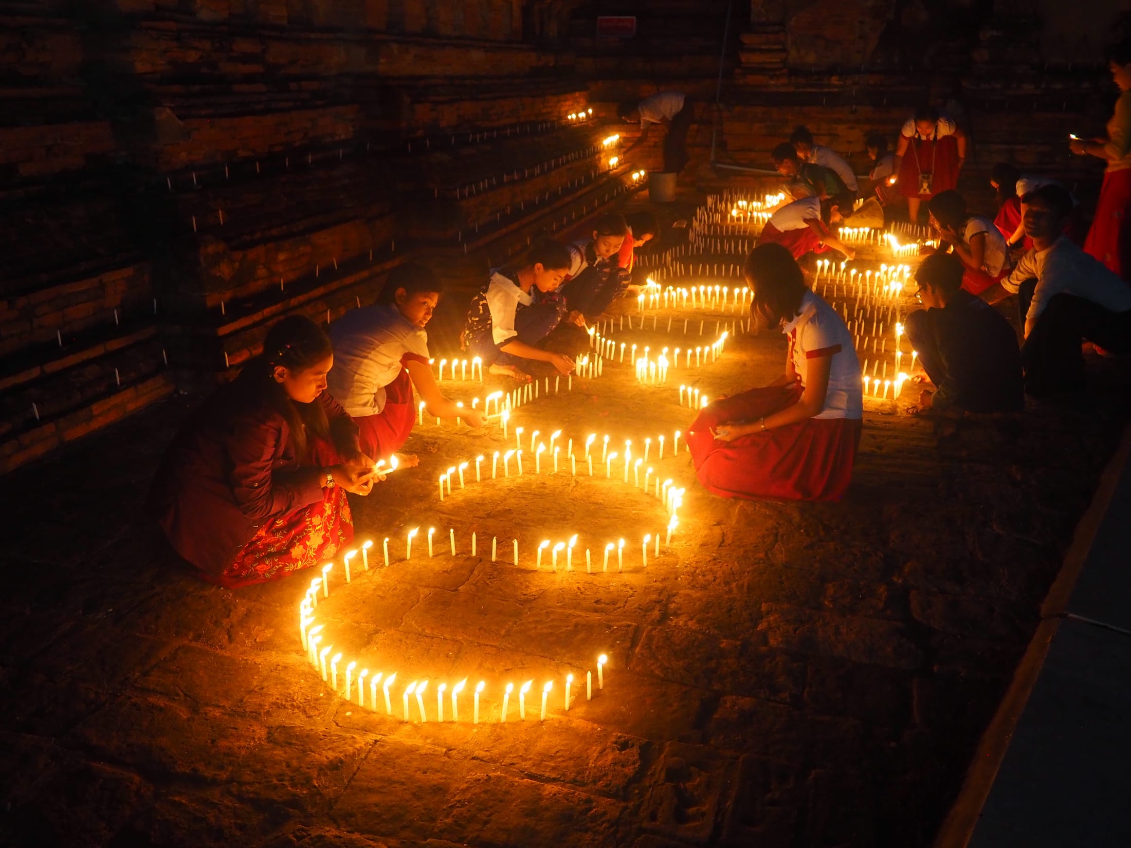 Children kneel to light spiralling arrangements of candles inside an ancient Bagan temple for the Thadingyut Festival of Lights