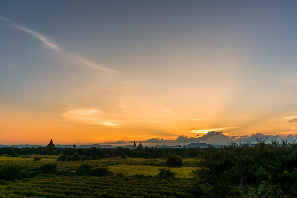 Silhouetted stupas of the Bagan temple plain against a glowing orange sunset sky